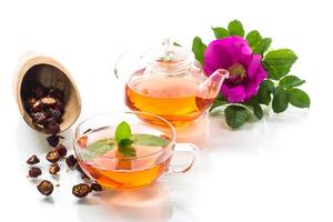 fabricado Rosa Mosqueta chá dentro uma vidro chaleira com Rosa Mosqueta flores e hortelã foto
