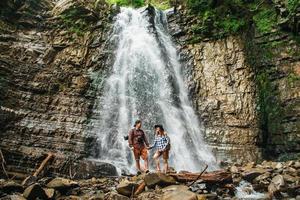 caminhantes homens e mulheres caminhando por um caminho rochoso contra o fundo de uma cachoeira e pedras foto