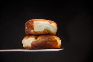 frito tortas preenchidas com fermento massa em uma de madeira remo, isolado em uma Preto fundo. foto