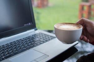 casual homem segurando café copo com computador portátil dentro escritório foto