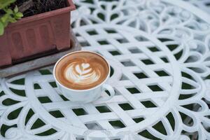 café quente café com leite com flor forma dentro branco copo em retro mesa foto