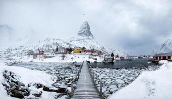 panorama do pescaria Vila dentro neve íngreme montanha com de madeira ponte foto