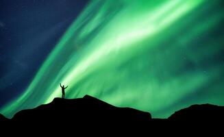 alpinista em pé em topo do montanha com aurora boreal brilhando dentro a noite céu em ártico círculo foto