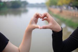 mulher elevado dela mãos e fez coração símbolo para expressar significado do amor amizade e bondade para dela amigos e amantes. mulher usa dela mãos para faço uma coração símbolo este significa amor e amizade. foto