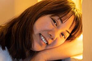 fechar-se do jovem japonês mulher sorridente e olhando às Câmera em amarelo fundo. foto