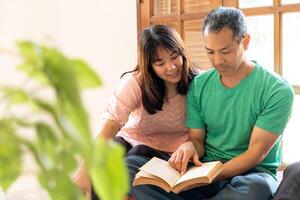 dois ásia adultos lendo uma livro, partilha uma momento do estude e conhecimento foto