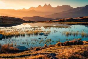 nascer do sol brilha sobre laca guichard com Arves maciço e lago reflexão dentro outono às aiguilles d’arves, francês Alpes, França foto