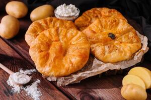 cozinhando tradicional tortas com batata em de madeira borda foto