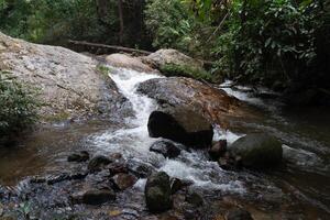 a corrente fluindo ao longo a rochoso falésias do chae filho cascata. background do floresta. às chae filho nacional parque tailândia. foto