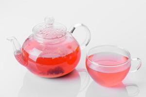 delicioso chá de bagas e frutas em um lindo bule de vidro em um fundo branco com reflexo foto