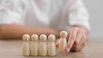 hr Gerente humano Recursos ou do empregador mão escolhe para levar pessoa de madeira boneca. a líder carrinhos Fora a partir de a multidão. olhando para Boa trabalhador. hora, hrm, hrd conceitos. foto