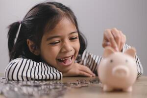 menina asiática economizando dinheiro em um cofrinho, aprendendo sobre economia, criança economizando dinheiro para educação futura. conceito de dinheiro, finanças, seguro e pessoas foto