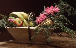 uma cesta preenchidas com fruta e flores em uma mesa foto