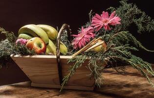 uma de madeira cesta preenchidas com fruta e flores foto