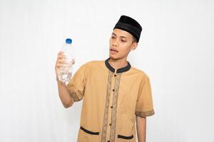 ásia muçulmano homem vestindo muçulmano roupas carregando mineral água dentro uma garrafa. isolado branco fundo. foto