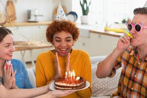 faço uma desejar. mulher vestindo festa boné sopro Fora queimando velas em aniversário bolo. feliz aniversário Festa. grupo do amigos desejos menina feliz aniversário. pessoas a comemorar aniversário com festa às casa foto