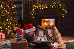 alegre Natal natal feriado. irmão irmãs crianças crianças lendo Magia Natal história livro perto Natal árvore dentro vivo quarto com lareira dentro inverno tarde. Natal véspera às casa foto