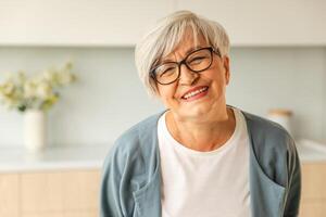 retrato do confiante à moda europeu meio envelhecido Senior mulher. Mais velho maduro anos 60 senhora sorridente às lar. feliz atraente Senior fêmea olhando Câmera fechar acima face Tiros na Cabeça retrato. feliz pessoas foto