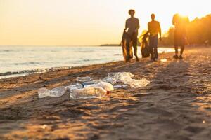terra dia. voluntários ativistas equipe coleta lixo limpeza do de praia costeiro zona. mulher mans com Lixo dentro lixo saco em oceano costa. de Meio Ambiente conservação costeiro zona limpeza foto