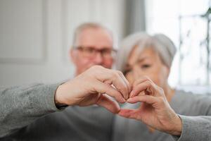 amor coração forma paz. Senior Mais velho casal fazer coração forma com seus mãos. adulto maduro velho marido esposa mostrando coração placa. feliz pensionista família. Eu amor você feliz dia dos namorados dia foto