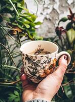 ai gerado café copo com flor impressão do mulher segurando dentro mão foto