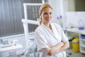 dentista feminina atraente posando em consultório odontológico moderno foto