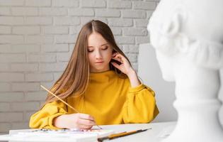 artista feminina pintando um quadro com aquarela no estúdio foto