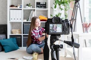 mulher fazendo um vídeo para seu blog sobre arte usando uma câmera digital montada em um tripé