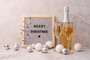feltro quadro de correspondência feliz natal na mesa com taças de champanhe e garrafa foto