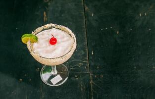 coco Margarita com cereja em de madeira mesa. congeladas coco coquetel com cereja em topo em de madeira mesa foto