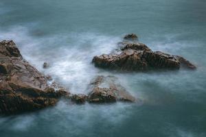 rochas e ondas à beira-mar foto