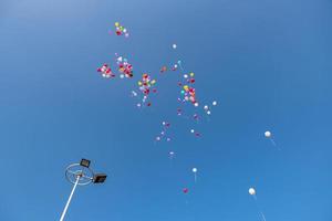balões de várias cores voando no céu azul foto