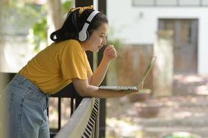 adolescente asiática usa laptop para trabalhar em casa.