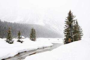 bela paisagem de inverno no lago luise, com lago congelado, floresta coberta de neve e pessoas à distância. Canadá. foto