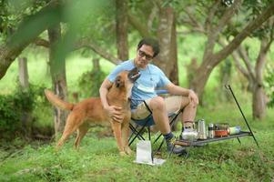 homem relaxando com o cachorro durante o acampamento. foto