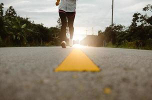 corredores femininos correndo na trilha de estrada no treinamento matinal para a maratona e fitness. conceito de estilo de vida saudável. atleta correndo exercício ao ar livre. pernas de close-up.