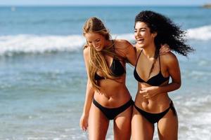 duas mulheres jovens com belos corpos em trajes de banho em uma praia tropical foto