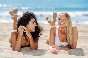 duas mulheres jovens com belos corpos em maiô em uma praia tropical foto