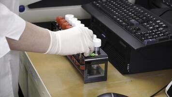 fêmea médico ou científico investigador usando teste tubos em laboratório. grampo. fêmea cientista análises líquido dentro a taça e tipos baixa observações em dela computador. ela é trabalhando dentro uma laboratório foto