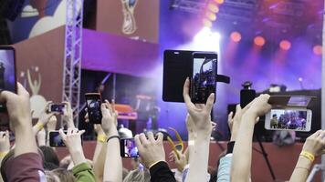 grupo do jovem pessoas desfrutando ao ar livre música festival. fechar-se traseiro Visão do multidão em show. engraçado pessoas tiro uma show em a telefone foto