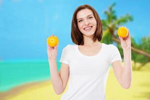 sorriso lindo mulher sexy com pele limpa e dentes brancos segurando tangerinas na praia e conceito de férias de verão tropical foto