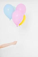 mão segurando balões. conceito de férias. fundo de balões de festa colorida. isolado no branco. copie o espaço foto