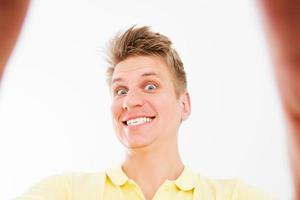 autorretrato de um cara selvagem bonito e atraente em uma camisa pólo amarela casual, sorriso com dentes brancos, isolado sobre um fundo branco brilhante foto