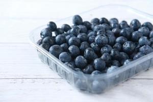 close-up de uma fruta azul fresca em um recipiente de plástico na mesa foto