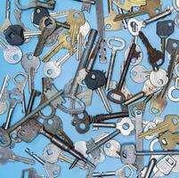 chaves em fundo azul. chaves de fechadura de porta e cofres para segurança da propriedade e proteção da casa. diferentes tipos de chaves antigas e novas. foto