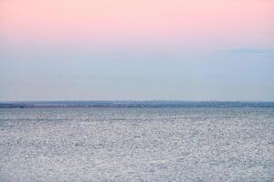 atmosférico romântico Rosa vermelho mar pôr do sol céu acima azul quieto água, minimalista pacífico marinha foto