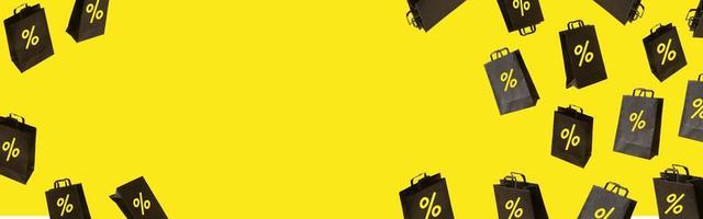 banner com sacolas de compras de venda preta estão voando sobre fundo amarelo. conceito criativo black friday foto