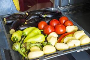 diferente legumes Berinjela tomates pimentas batatas em uma cozimento folha. foto