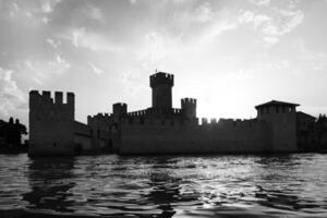 itália - silhueta do castelo sirmone no lago garda ao pôr do sol. arquitetura medieval com torre. foto