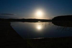 pôr do sol em uma lago dentro Suécia. a luar é refletido dentro a calma água. Escandinávia foto